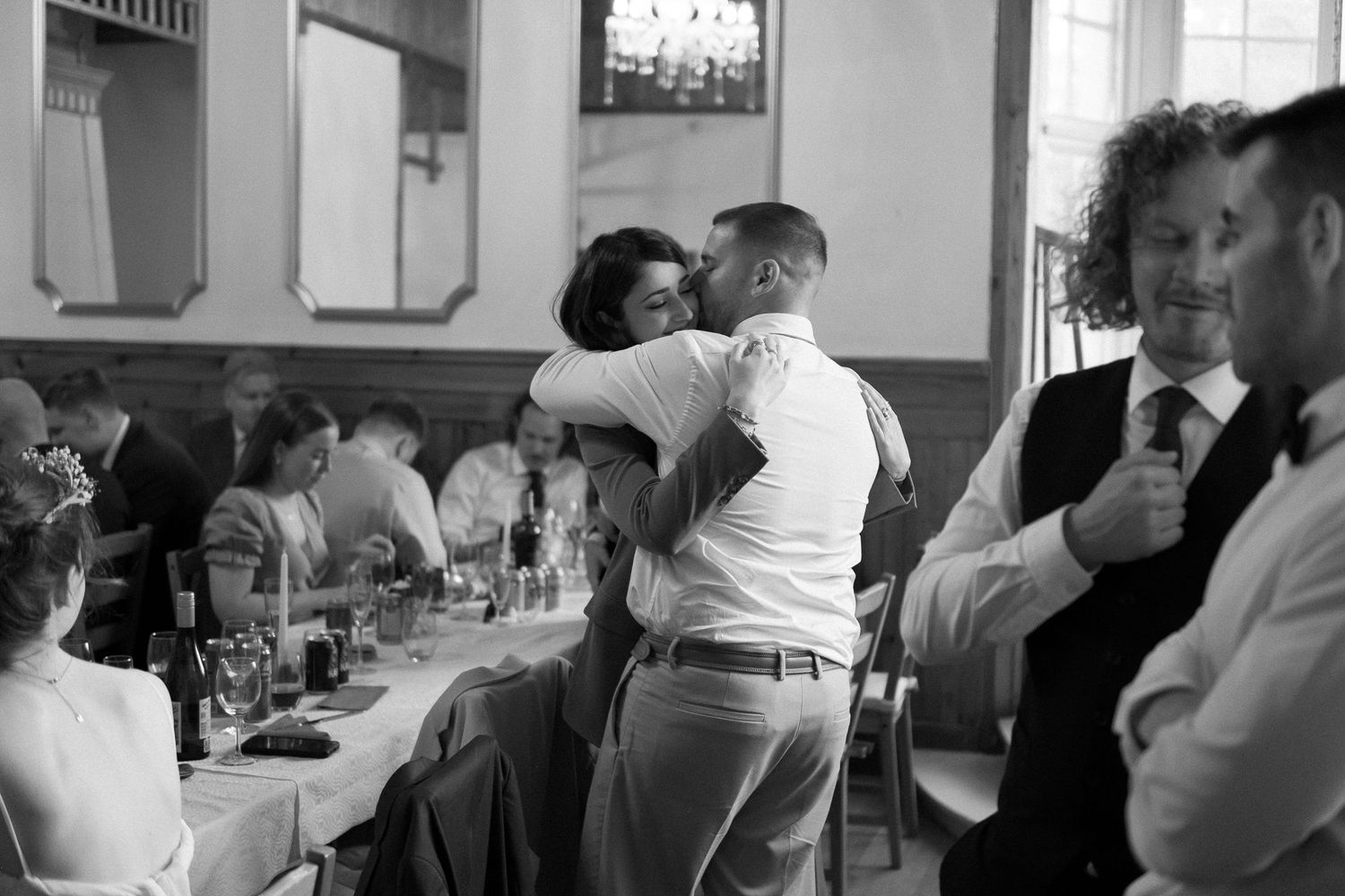 Black and white photo of guests mingling at a crowded reception dinner table.