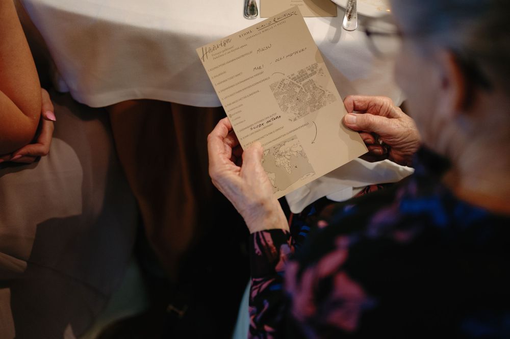 Hands holding and examining a document or menu at a formal dining table.