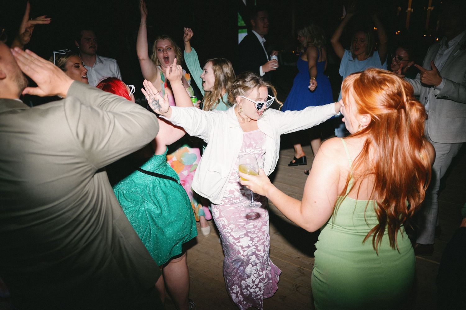 Energetic dance floor scene at a wedding reception with guests in colorful attire.