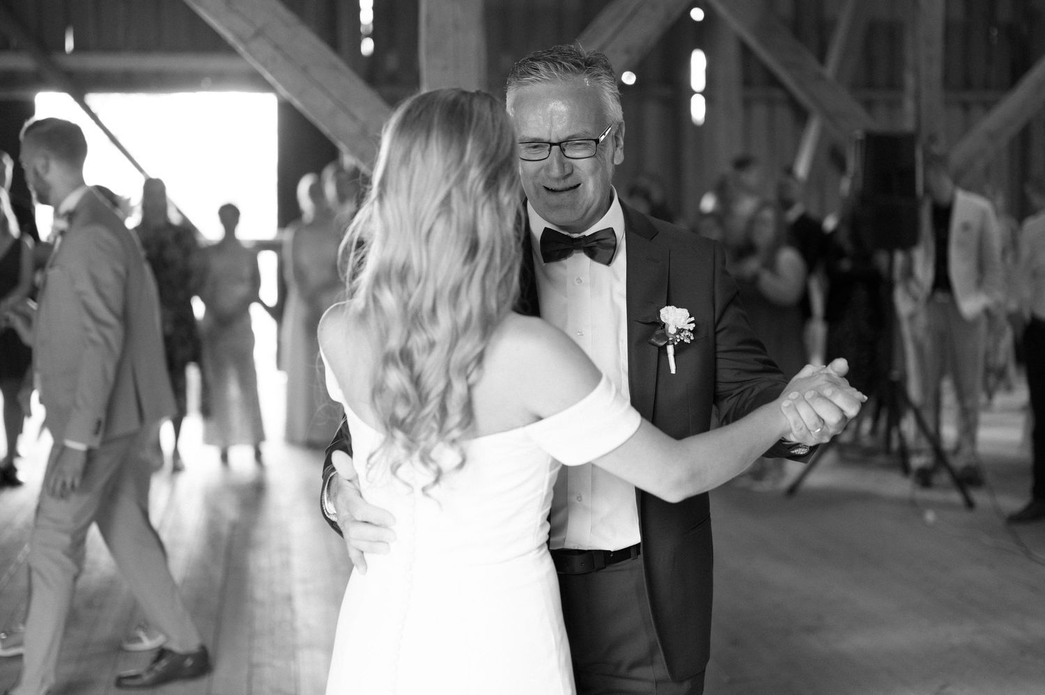 Wedding reception dance captured in black and white photography inside rustic barn setting.