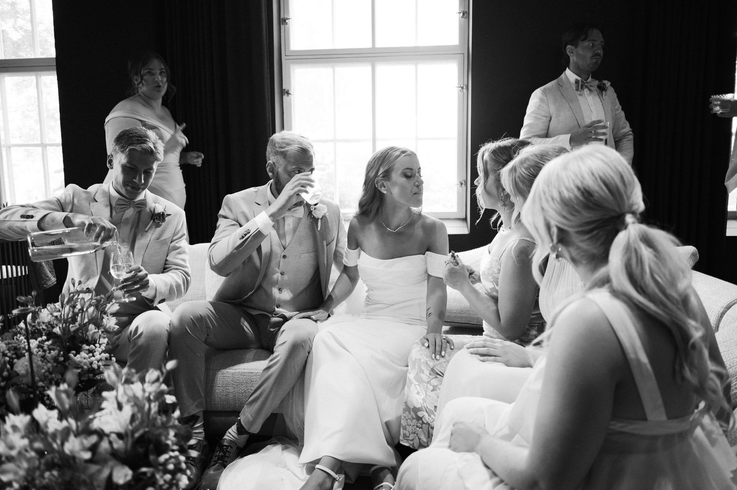Wedding guests seated at tables during a reception in a bright indoor venue.