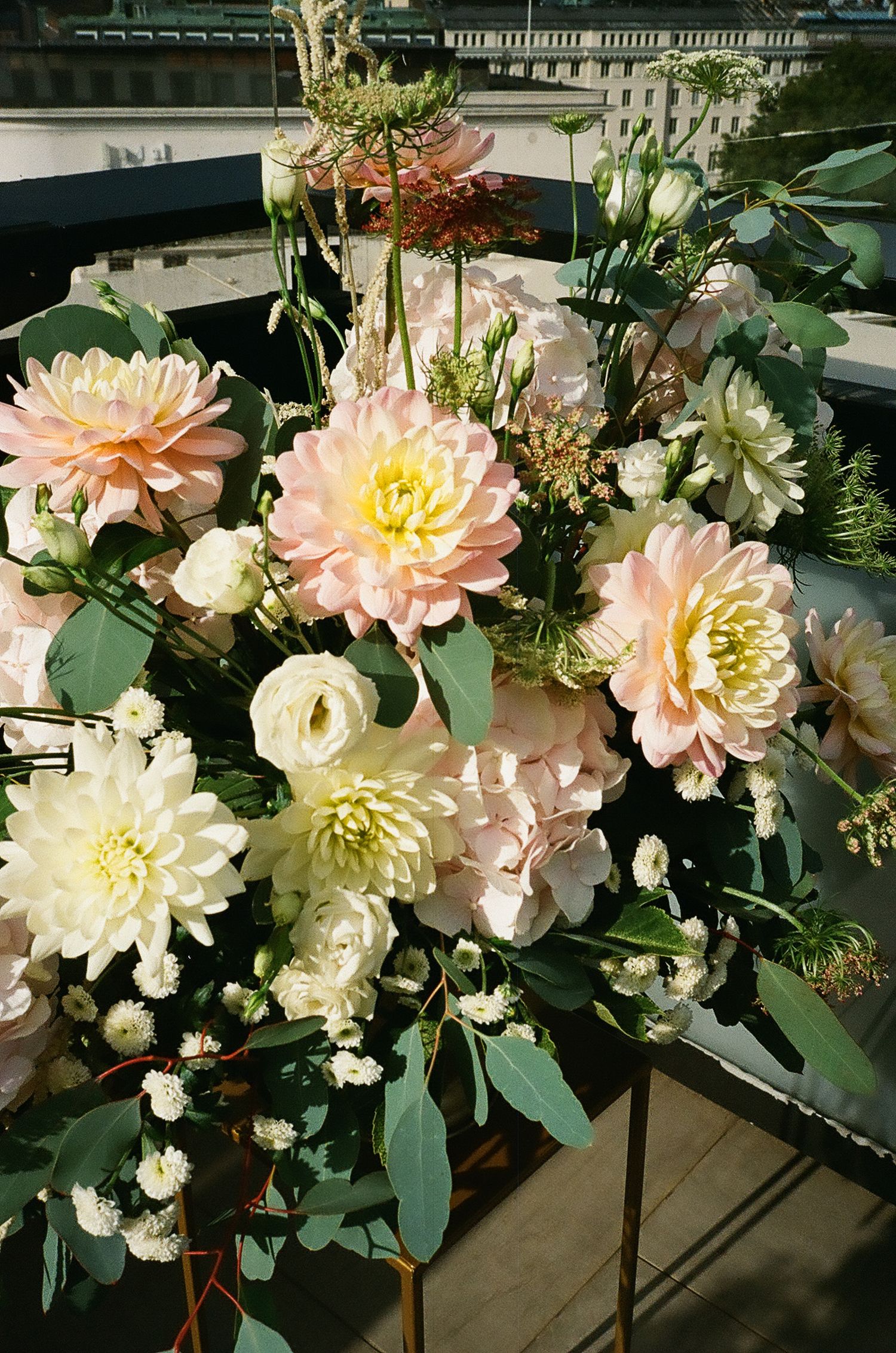 Beautiful arrangement of pink and cream dahlias with greenery in natural light.
