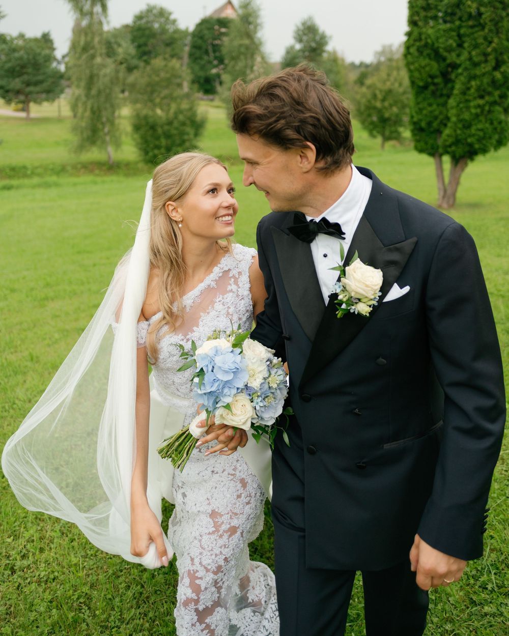 A couple shares an intimate moment in a lush green field during their wedding photoshoot.