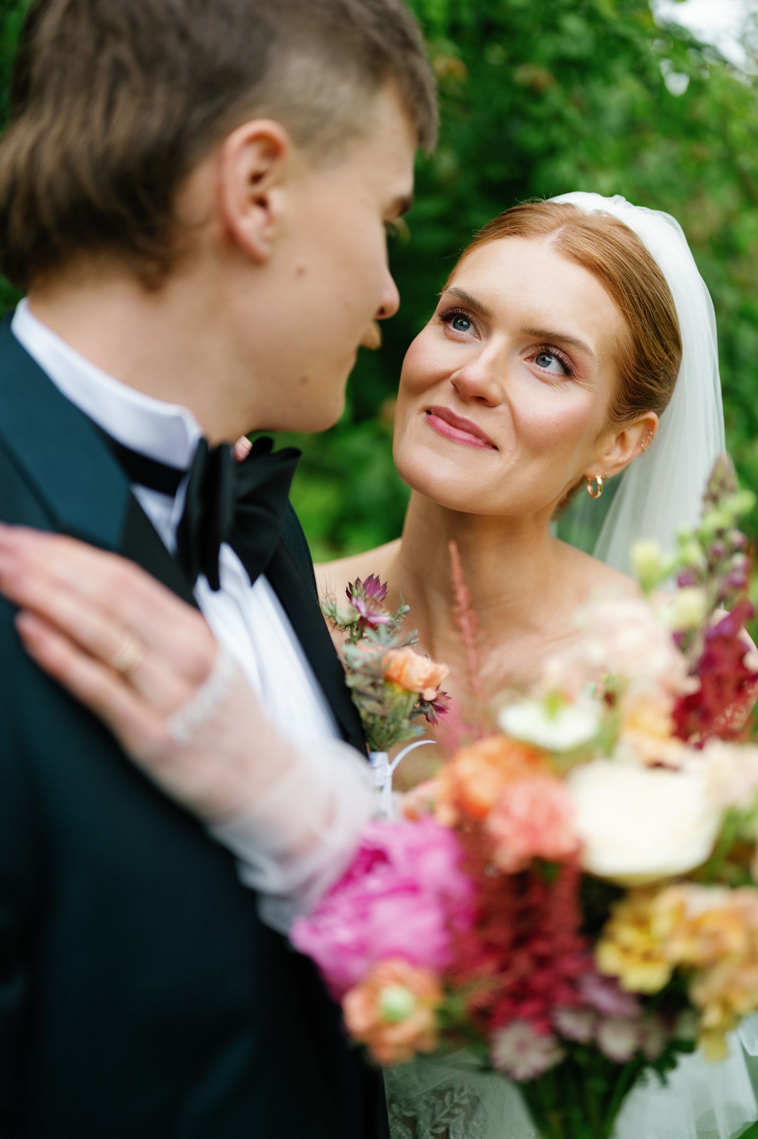 Wedding couple sharing an intimate moment among colorful summer flowers.