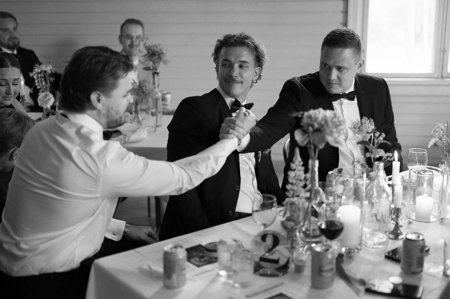 Guests in formal attire sharing drinks and conversation at a reception table.