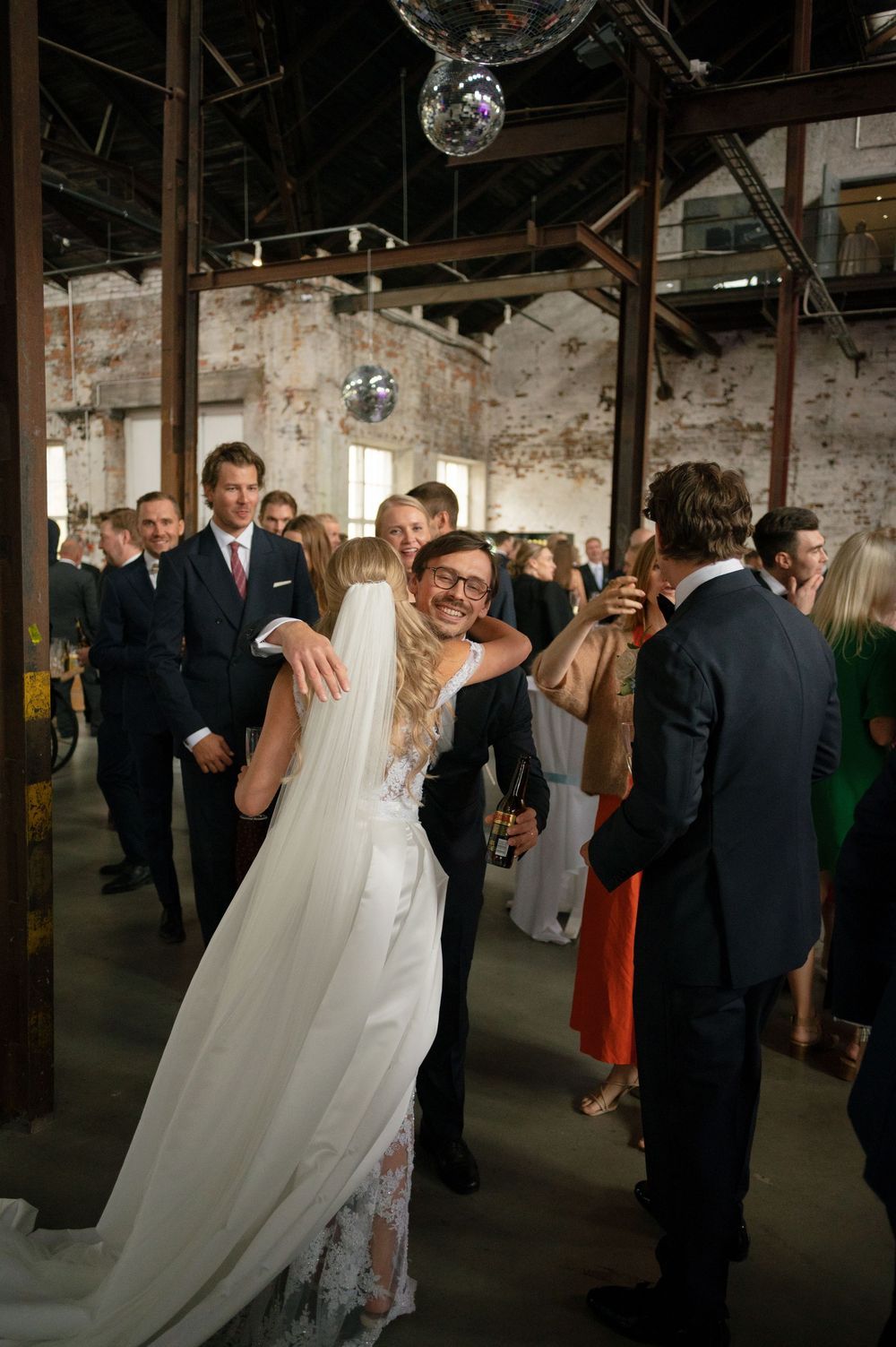 Wedding reception in a rustic venue with disco balls hanging from the ceiling.