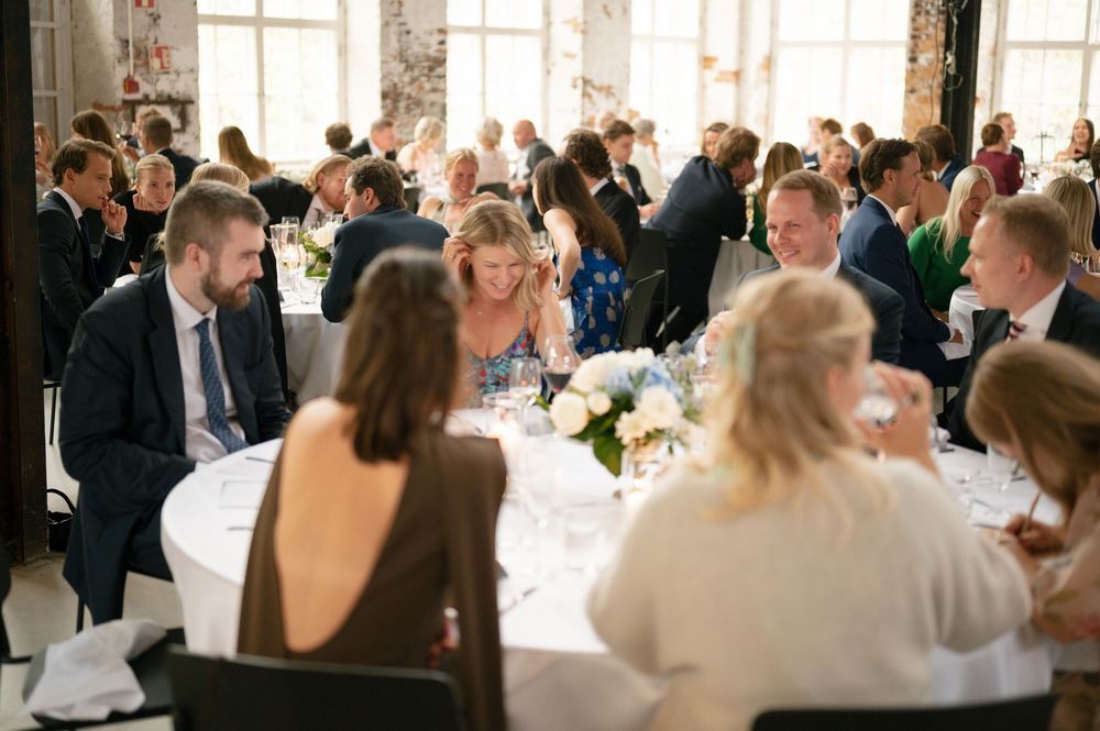 Elegant wedding reception venue with guests seated at long tables in a bright, airy space.