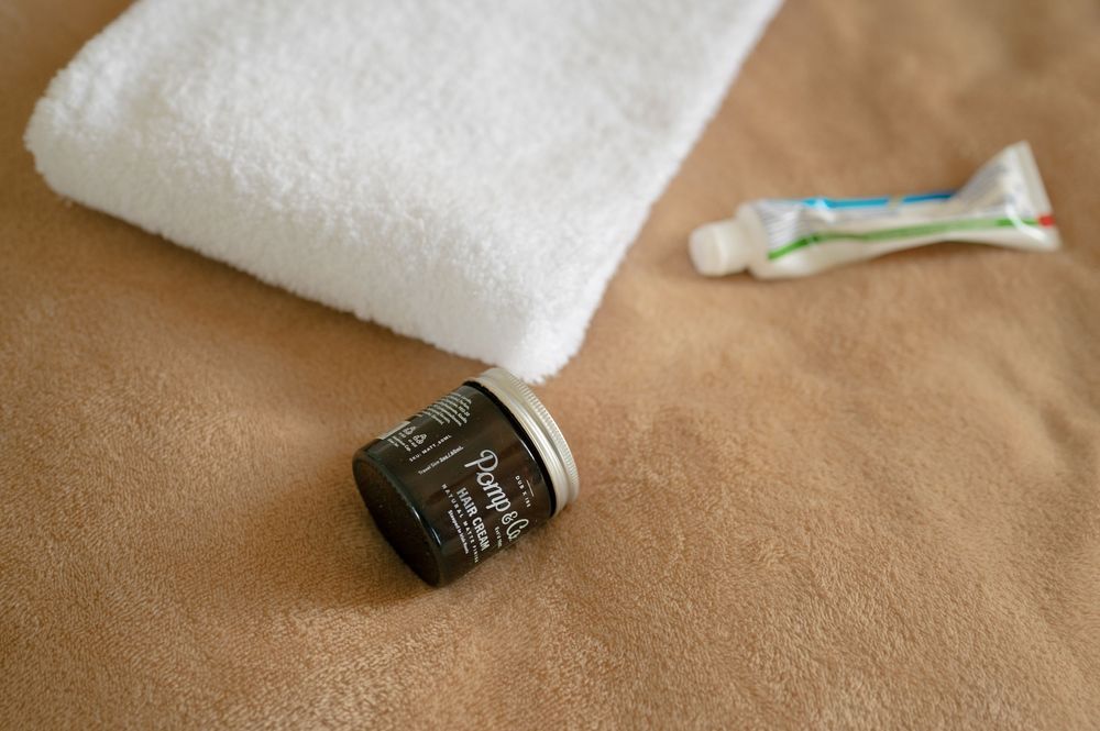 White towels and personal care items arranged on brown surface.