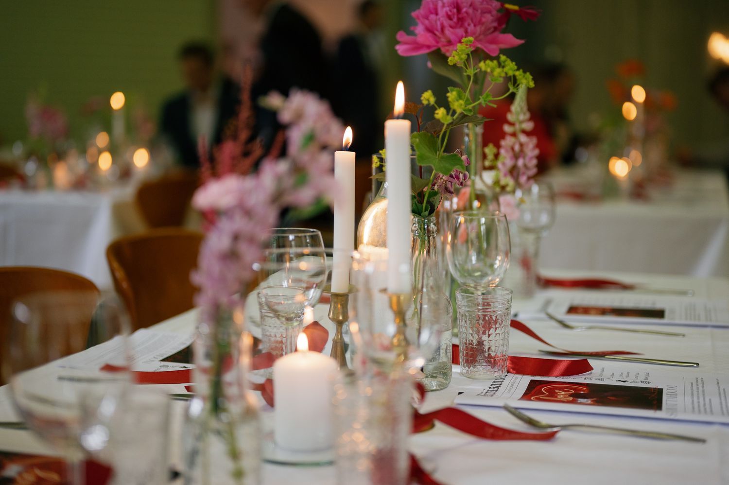 Romantic table setting with pink flowers and lit candles for wedding reception.