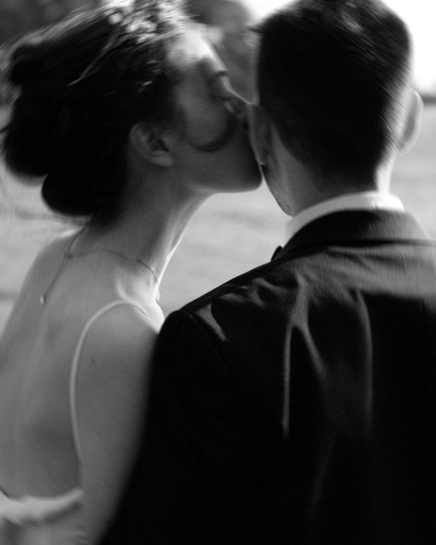 An intimate black and white portrait capturing a tender wedding day kiss.
