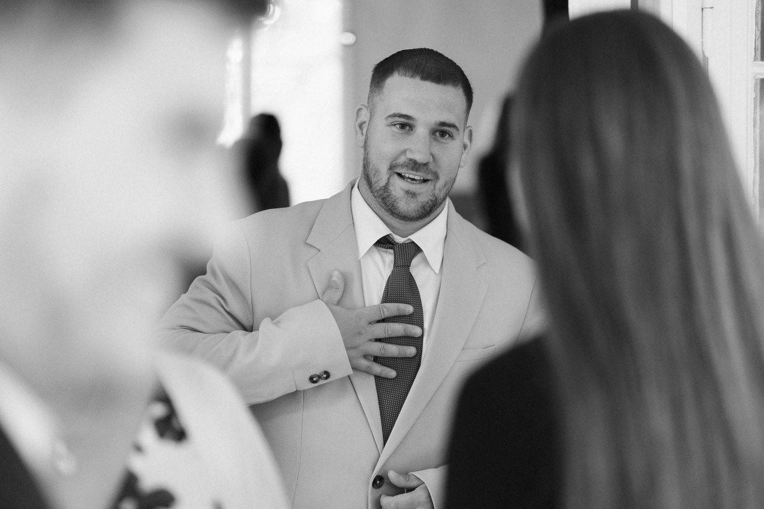 Black and white candid shots of wedding guests interacting at a celebration.