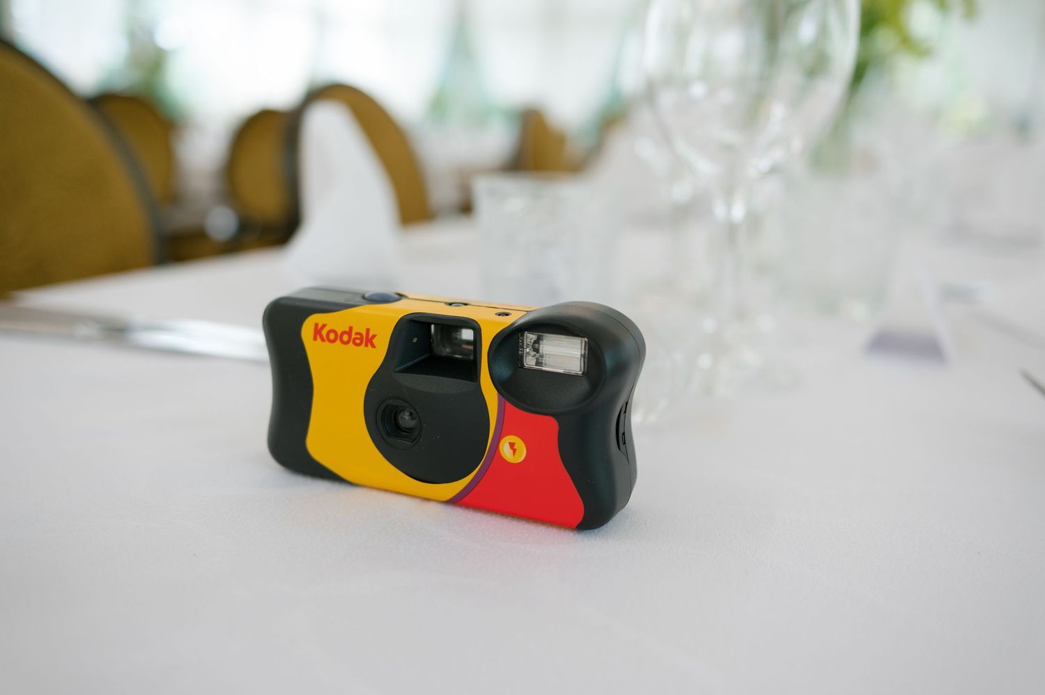 Disposable yellow and red cameras arranged on a white tablecloth at a wedding reception.