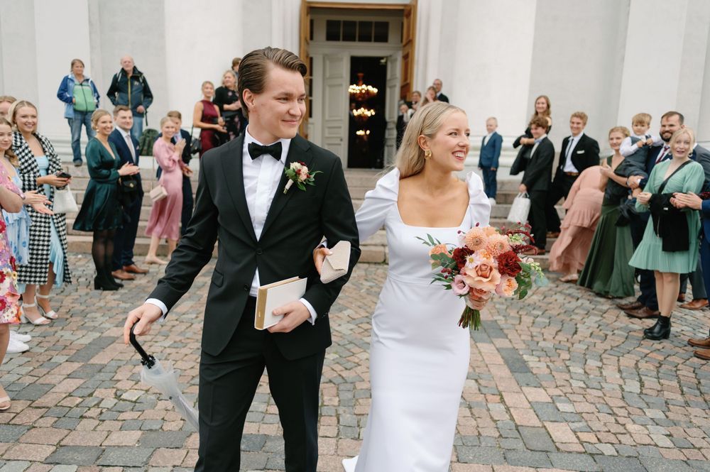 Wedding celebration on cobblestone courtyard with guests throwing confetti.