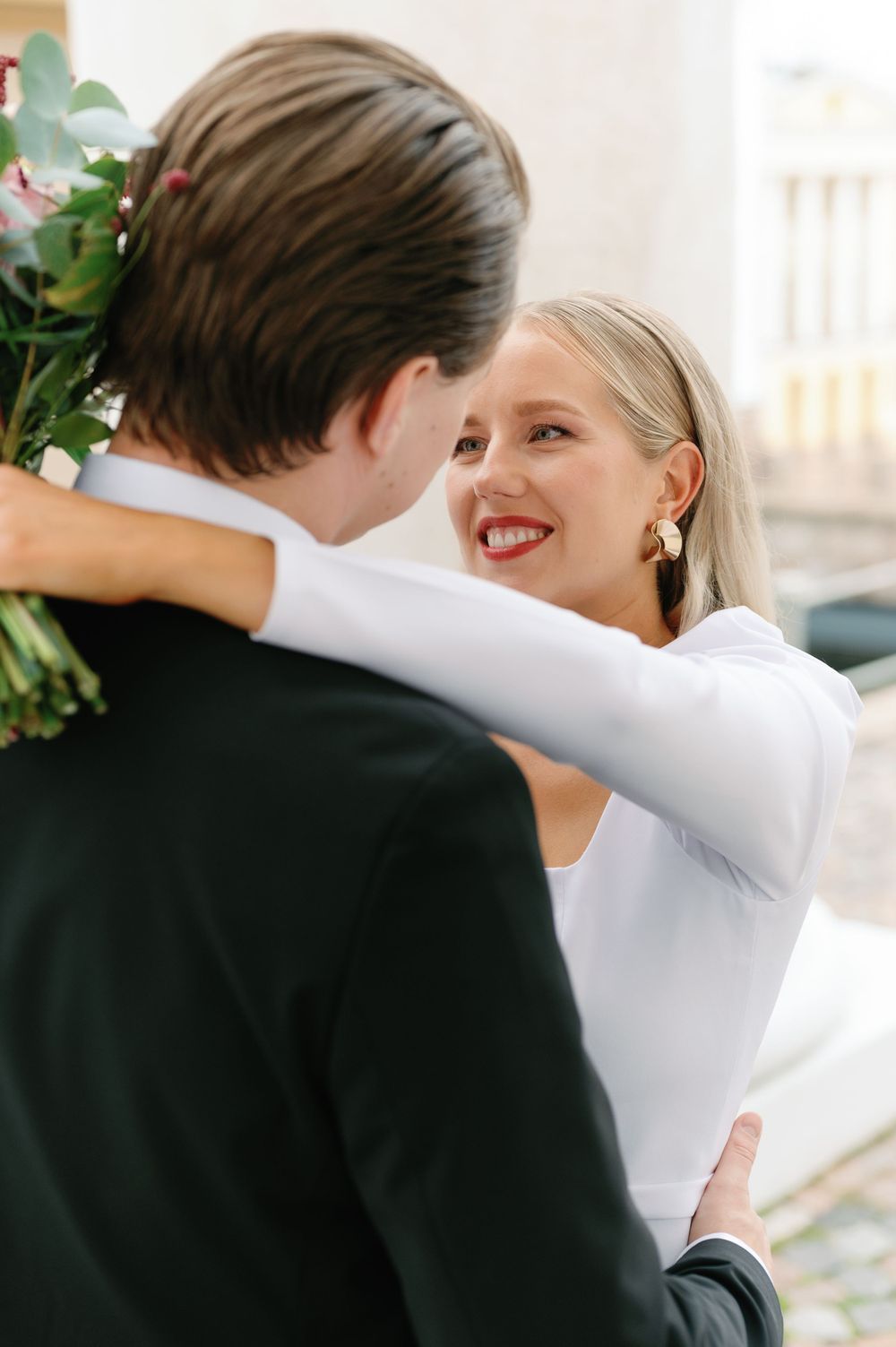 A romantic wedding portrait showing a couple sharing a close moment with coral flowers.