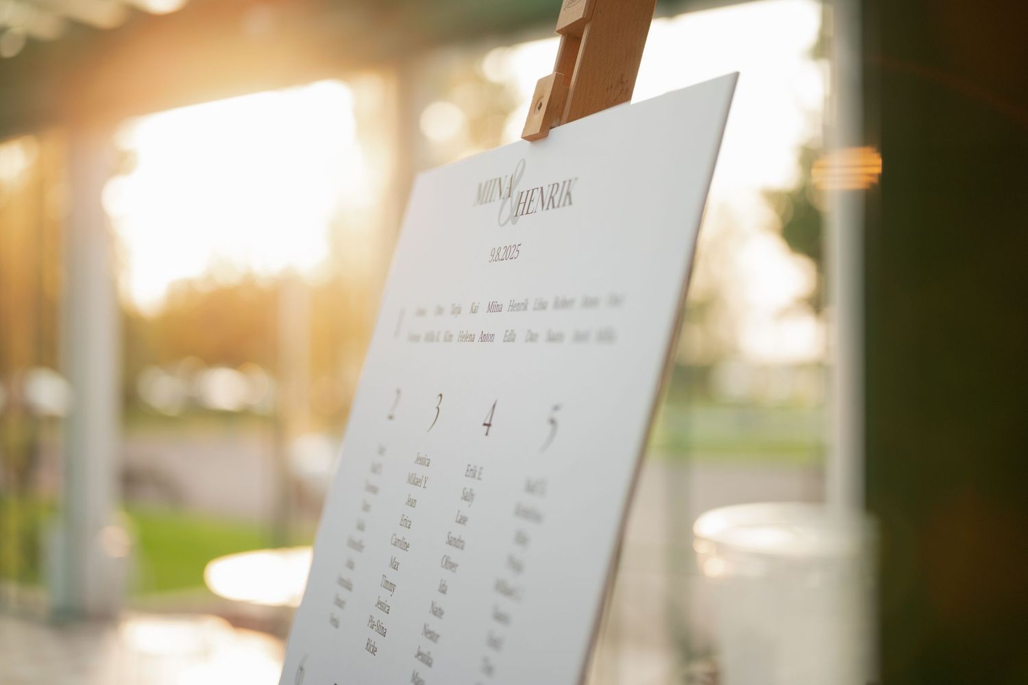 Soft-lit reception venue with elegant table settings and hanging decorative elements.