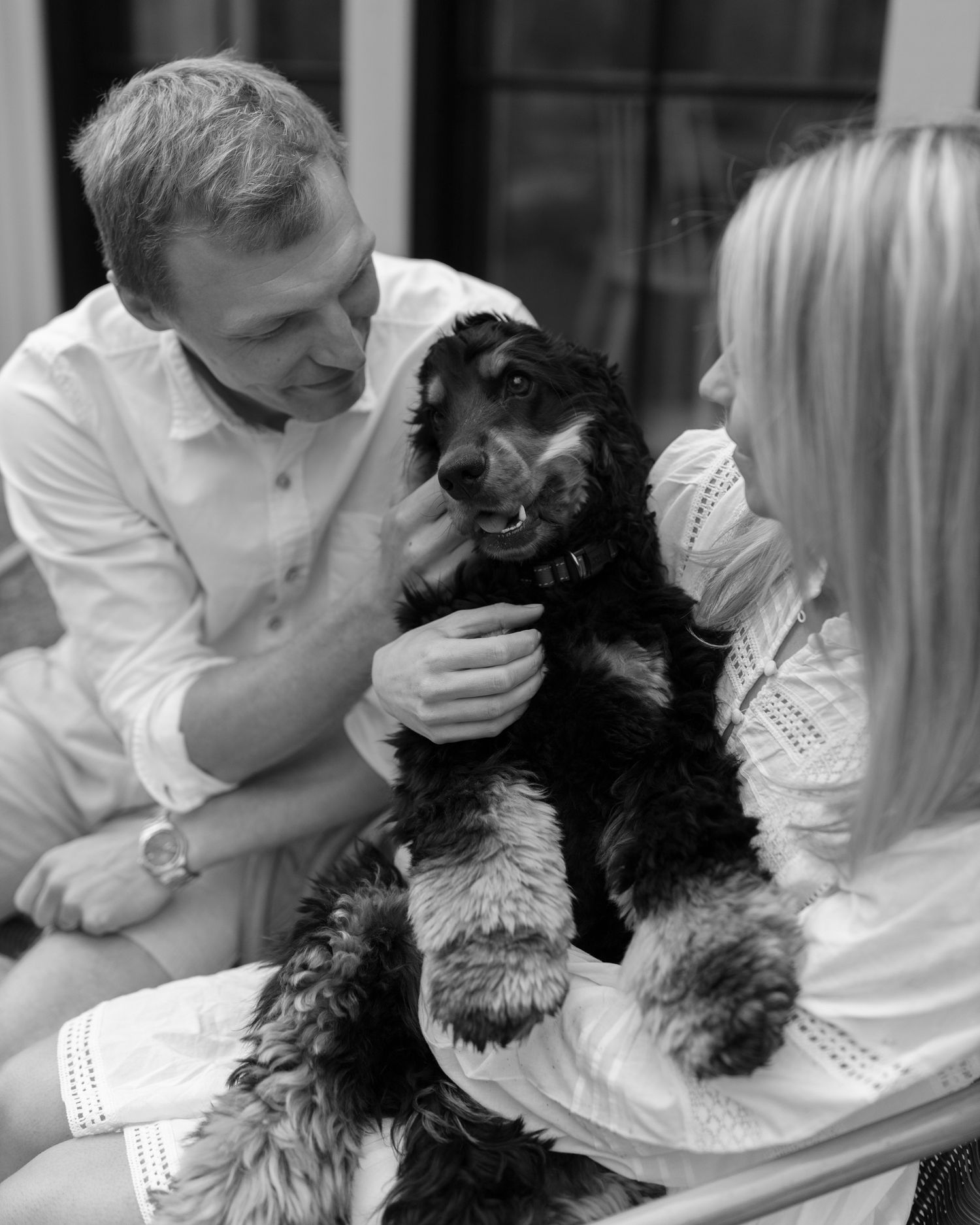 A black dog being held and cuddled in a series of affectionate photos.