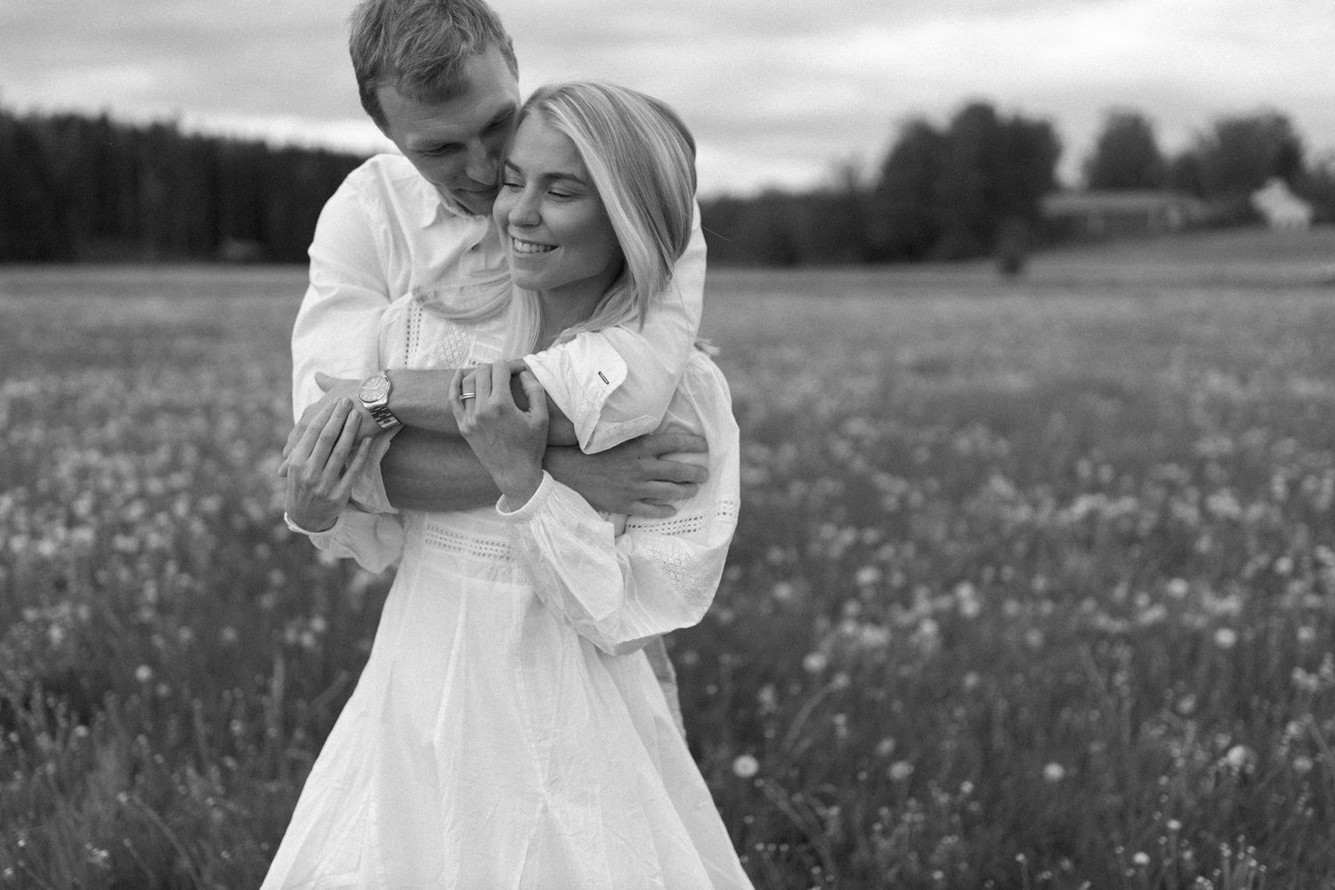 A tender black and white portrait of a couple embracing in a flowering meadow.