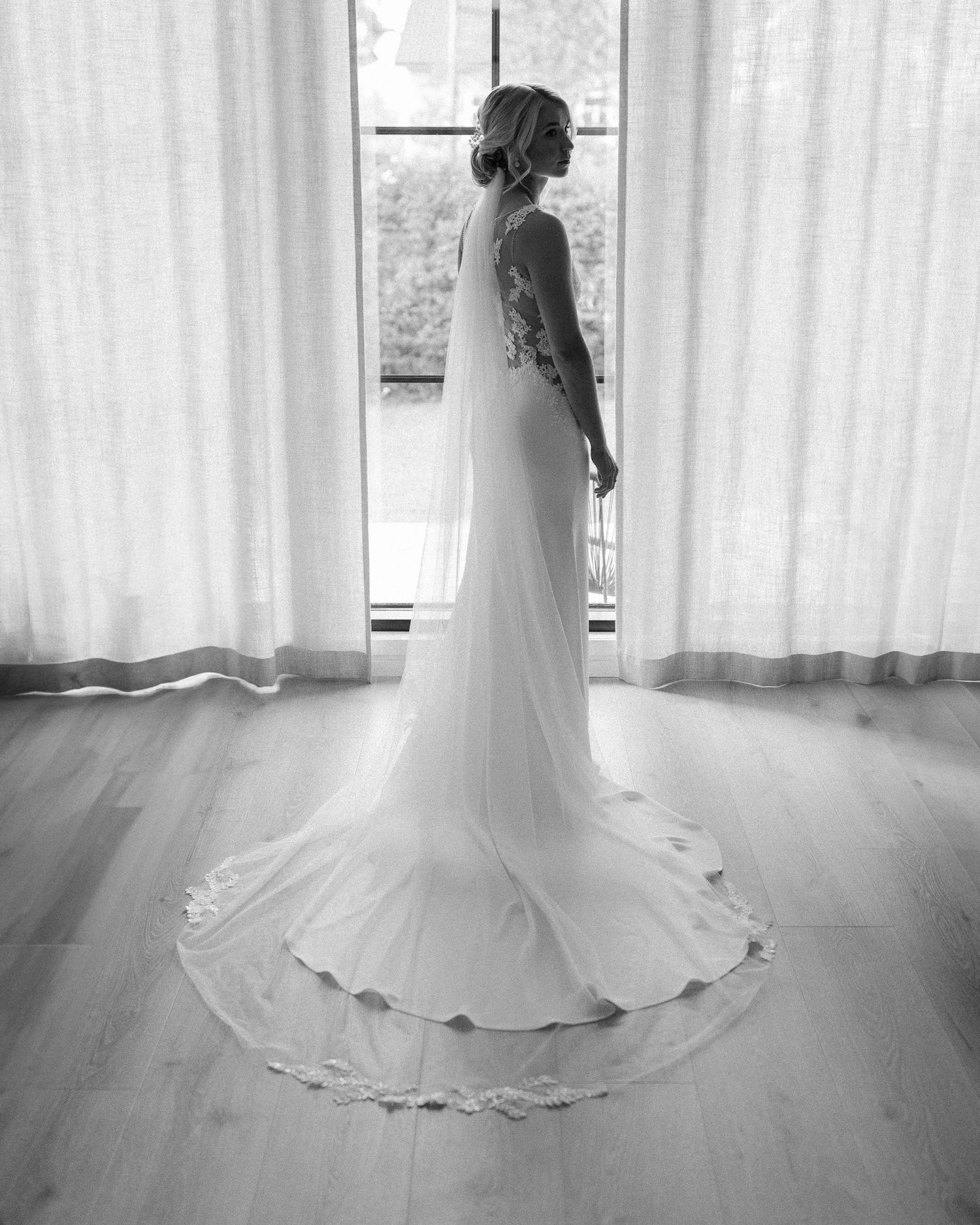 Black and white photo of a flowing wedding dress captured in a bright interior space.