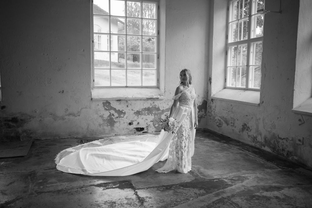 Black and white portrait of a bridal gown flowing in an abandoned room with natural light.