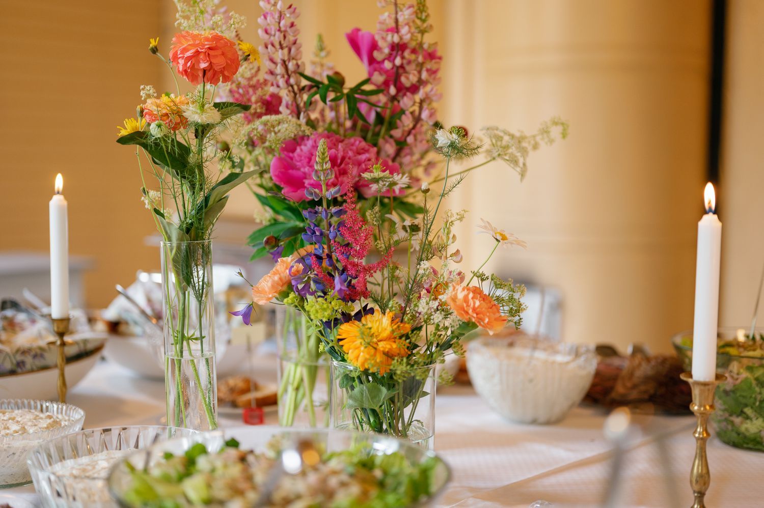 Colorful floral centerpieces with pink, orange and yellow blooms on elegant table settings.
