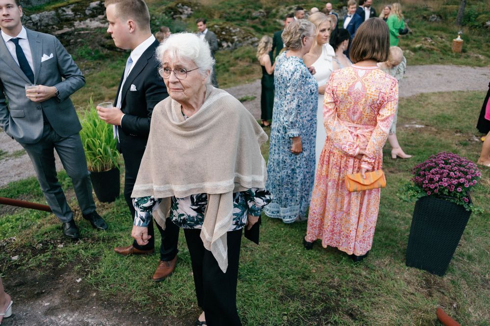 Wedding guests mingle outdoors on a grassy lawn during a daytime celebration.