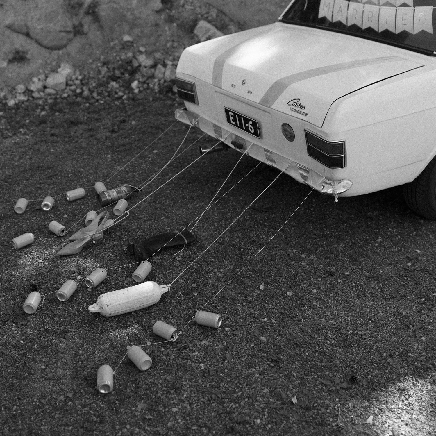 Black and white photo of vintage cars parked on rural hillside.