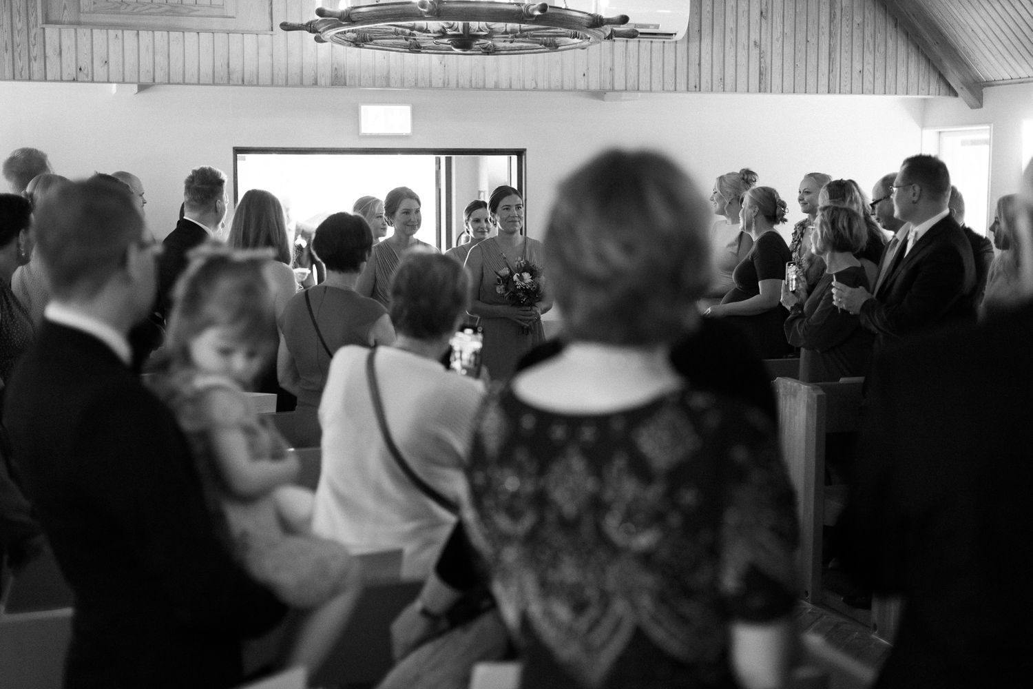 Black and white photo of wedding guests gathered inside a church during a ceremony.