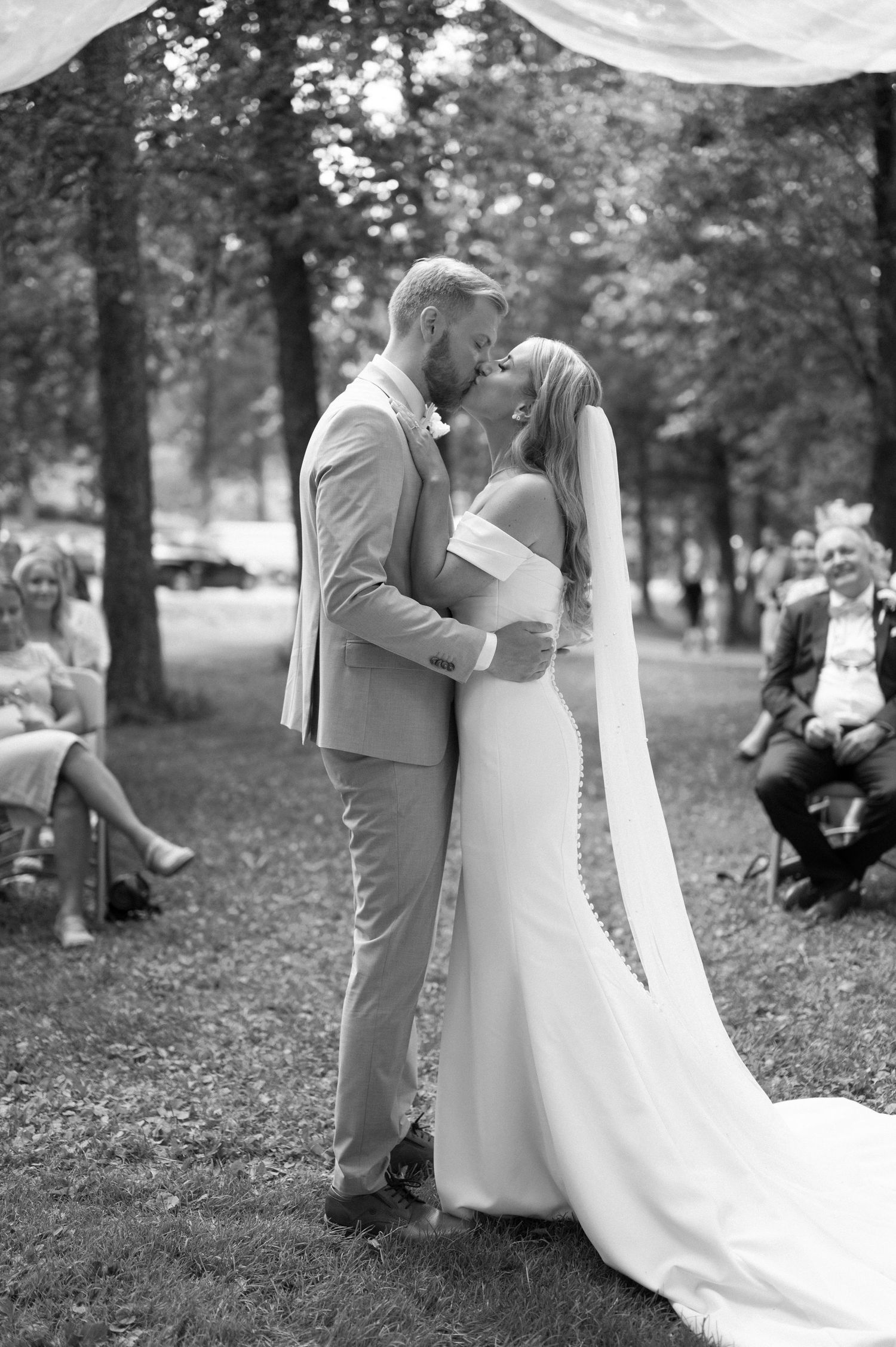 Black and white wedding photography capturing intimate moments in a natural outdoor setting.