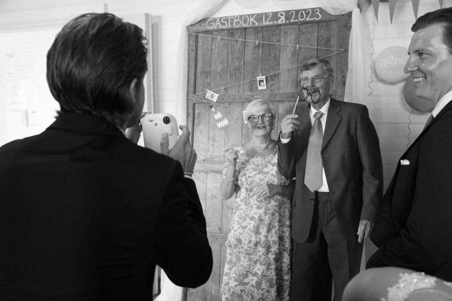 Black and white photo of wedding guests mingling at a reception.