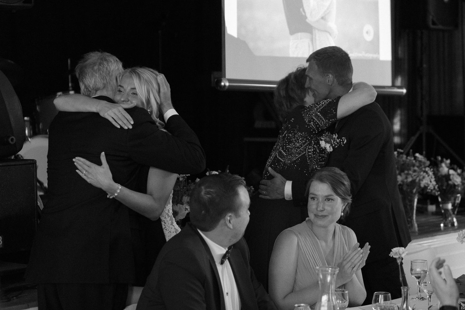 Wedding guests embracing during an emotional moment at the reception.