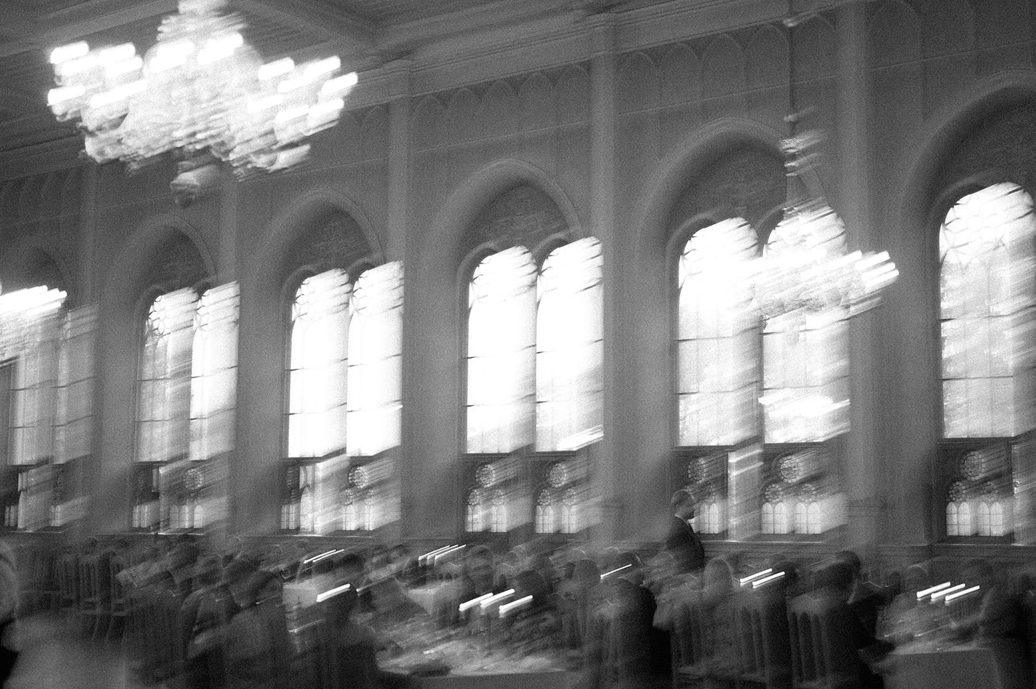 Blurred architectural interior showing arched windows and chandeliers in an elegant ballroom.