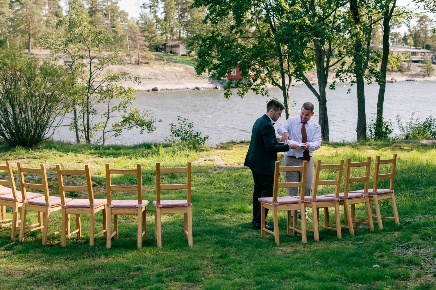 Outdoor wedding ceremony setup with wooden chairs facing waterfront.
