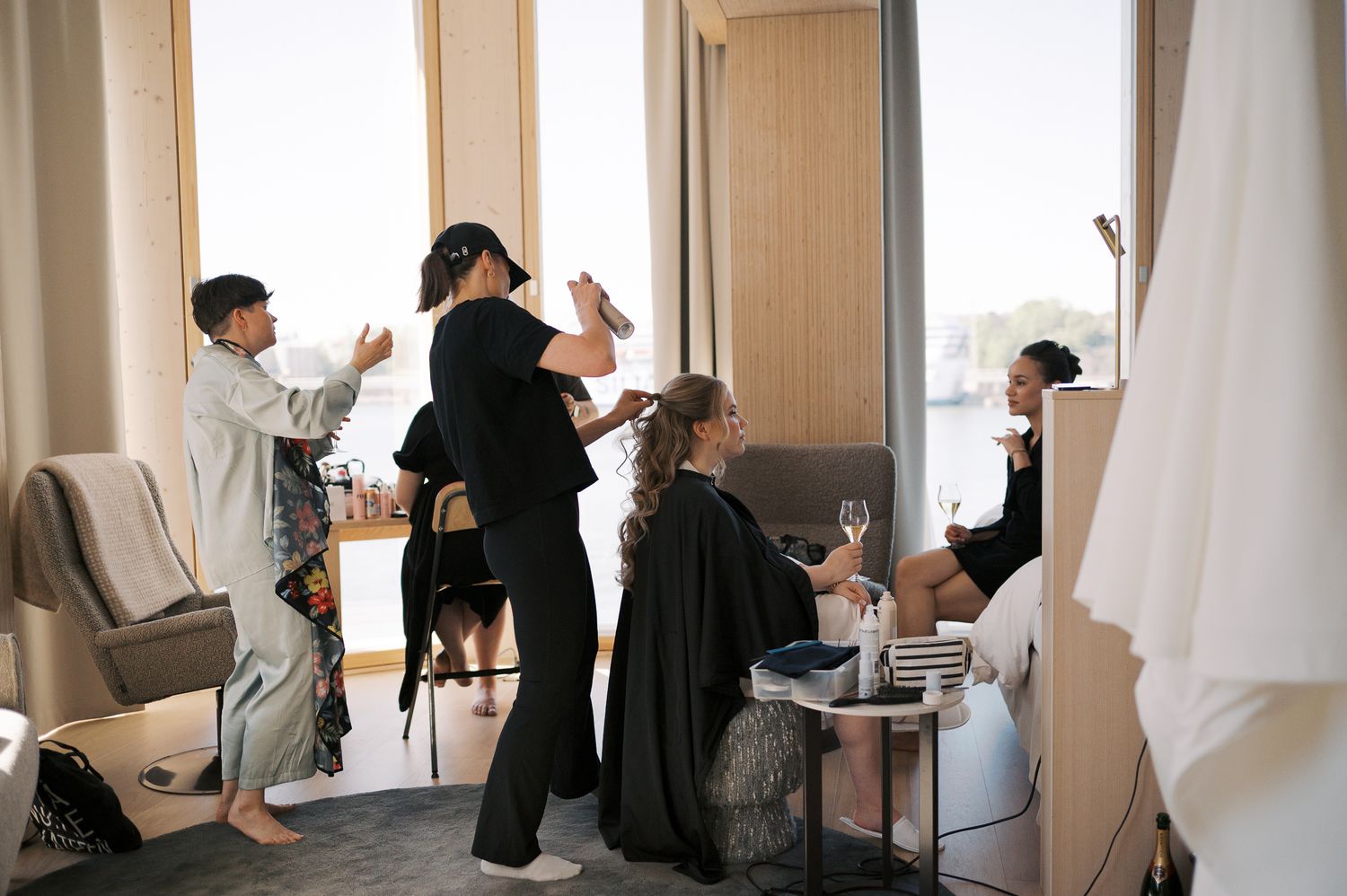 Bridal party getting ready in a hotel suite with hair stylists working on a bride before the wedding.