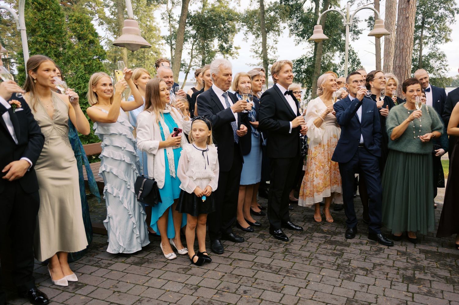 Wedding guests form a line on a brick patio during an outdoor celebration at dusk.