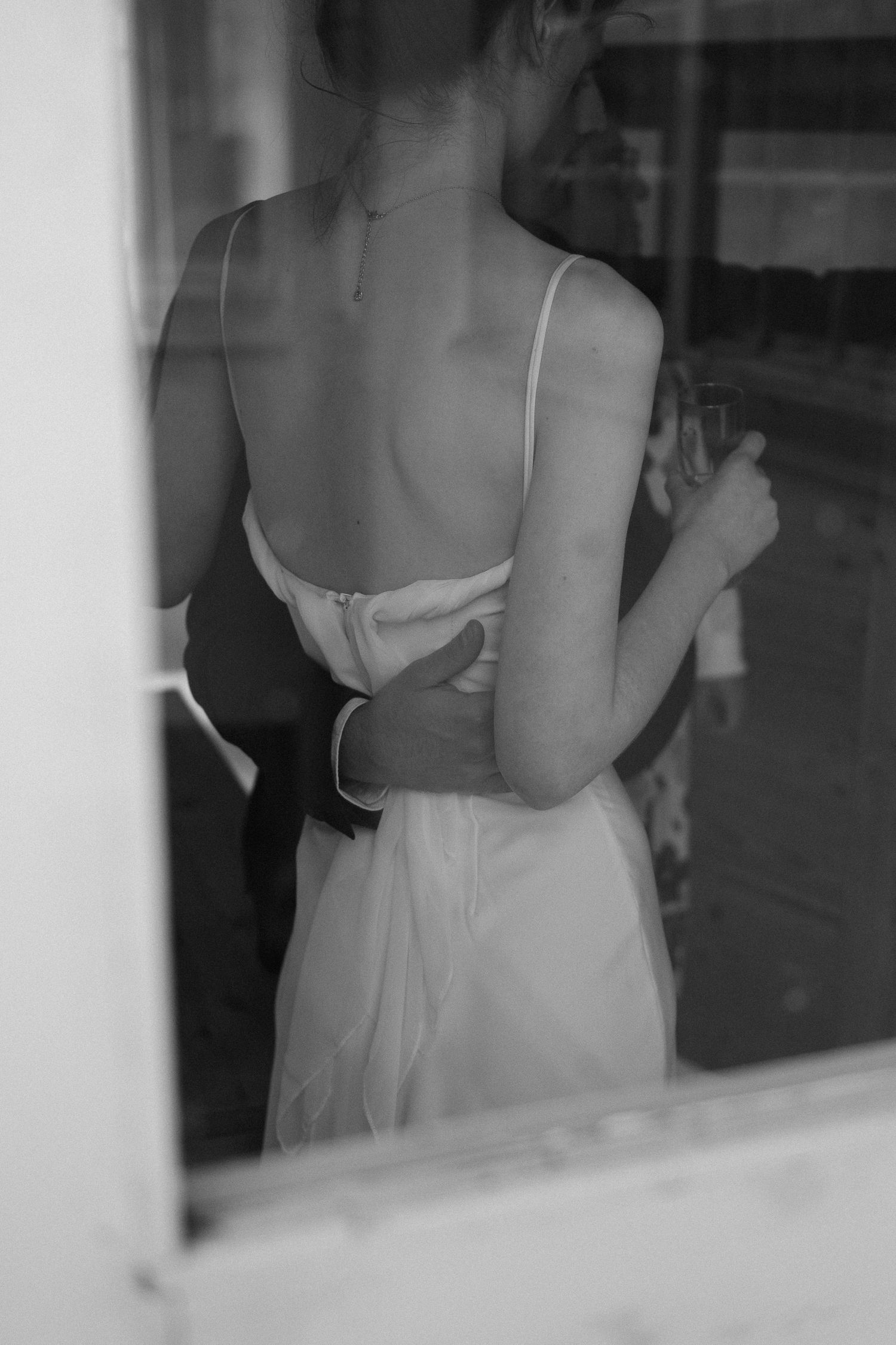 Black and white artistic photo showing the back detail of a formal white dress.
