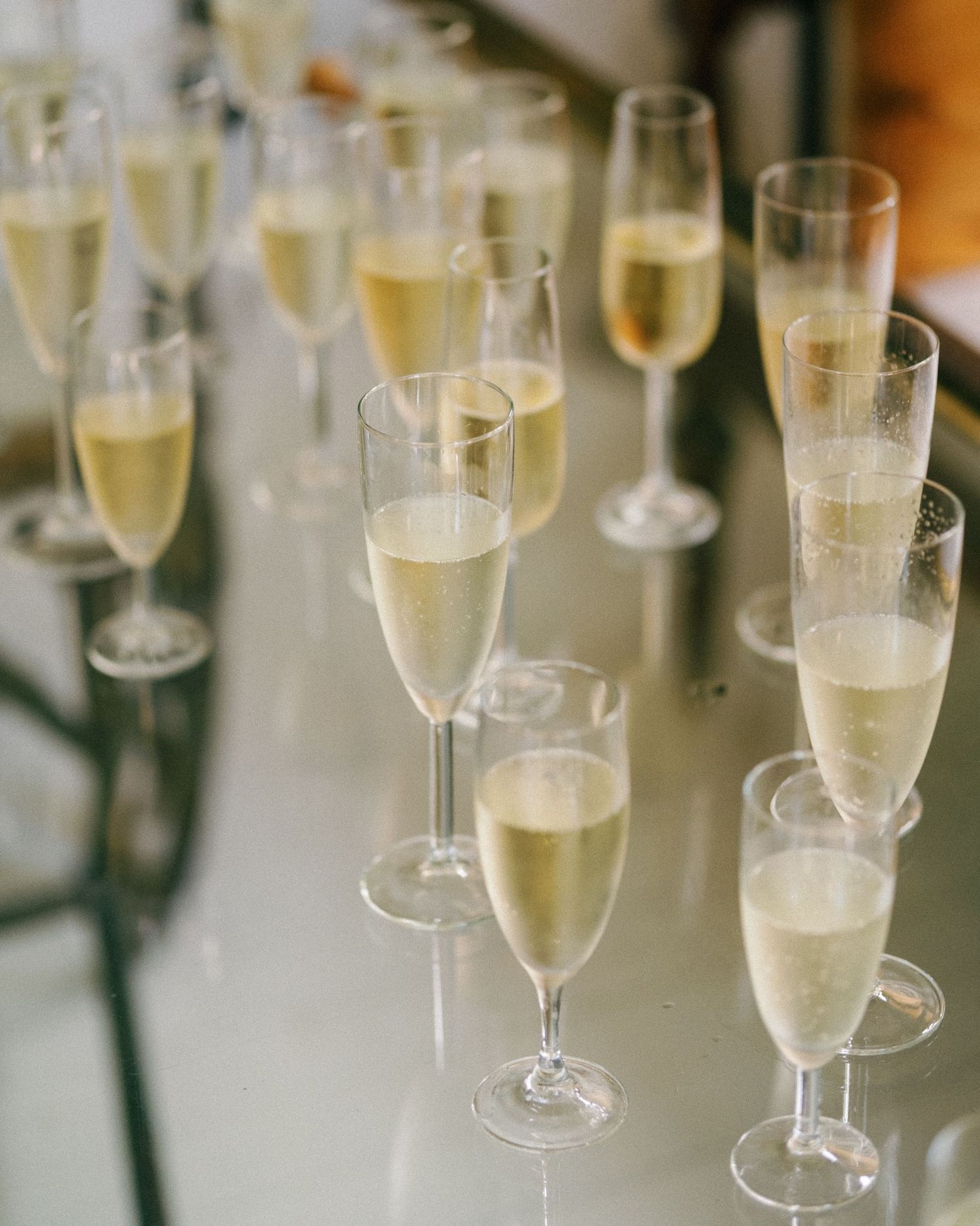 Elegant champagne flutes filled with sparkling wine arranged in a row at an event.