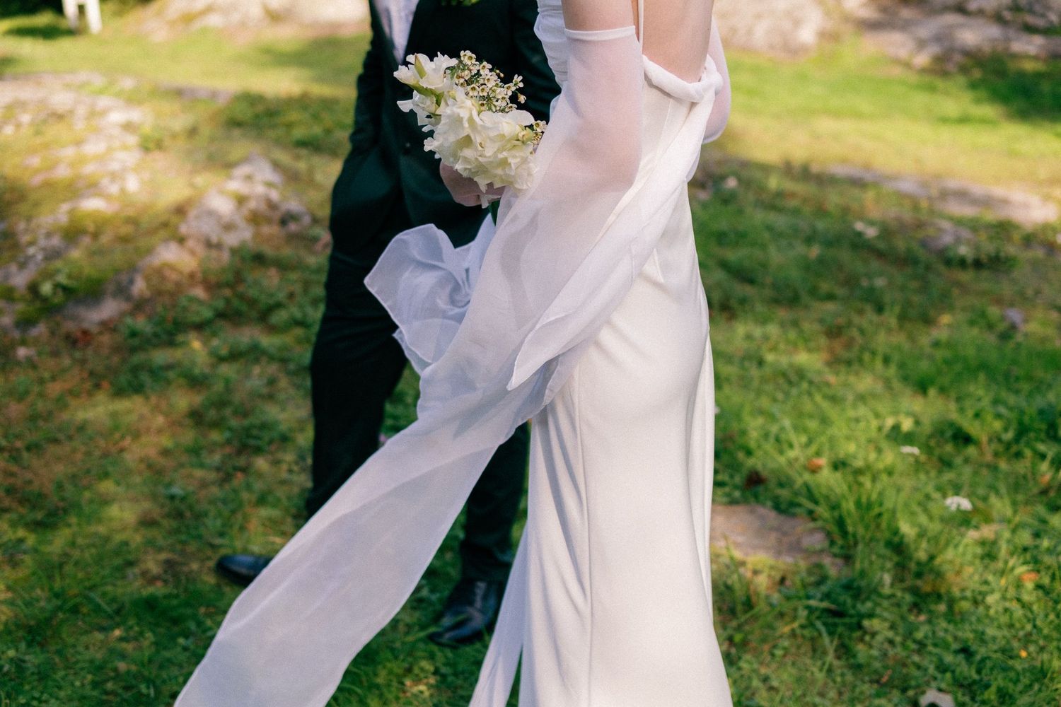 Elegant white wedding dress flowing in the breeze during an outdoor photoshoot.