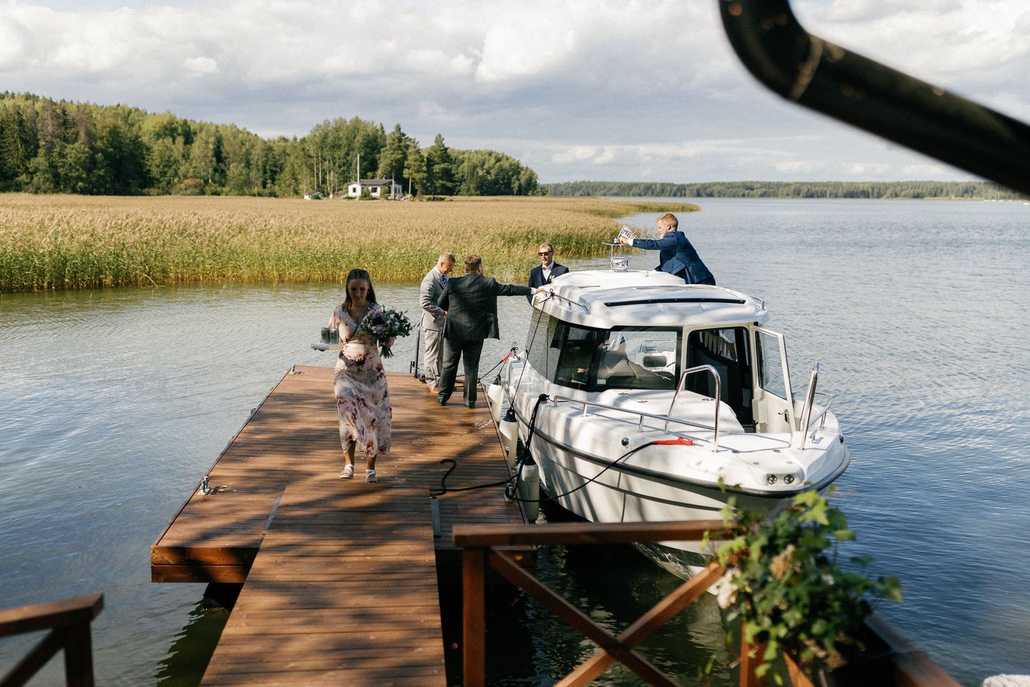 Wooden dock extends into lake with boats and trees visible along shoreline.
