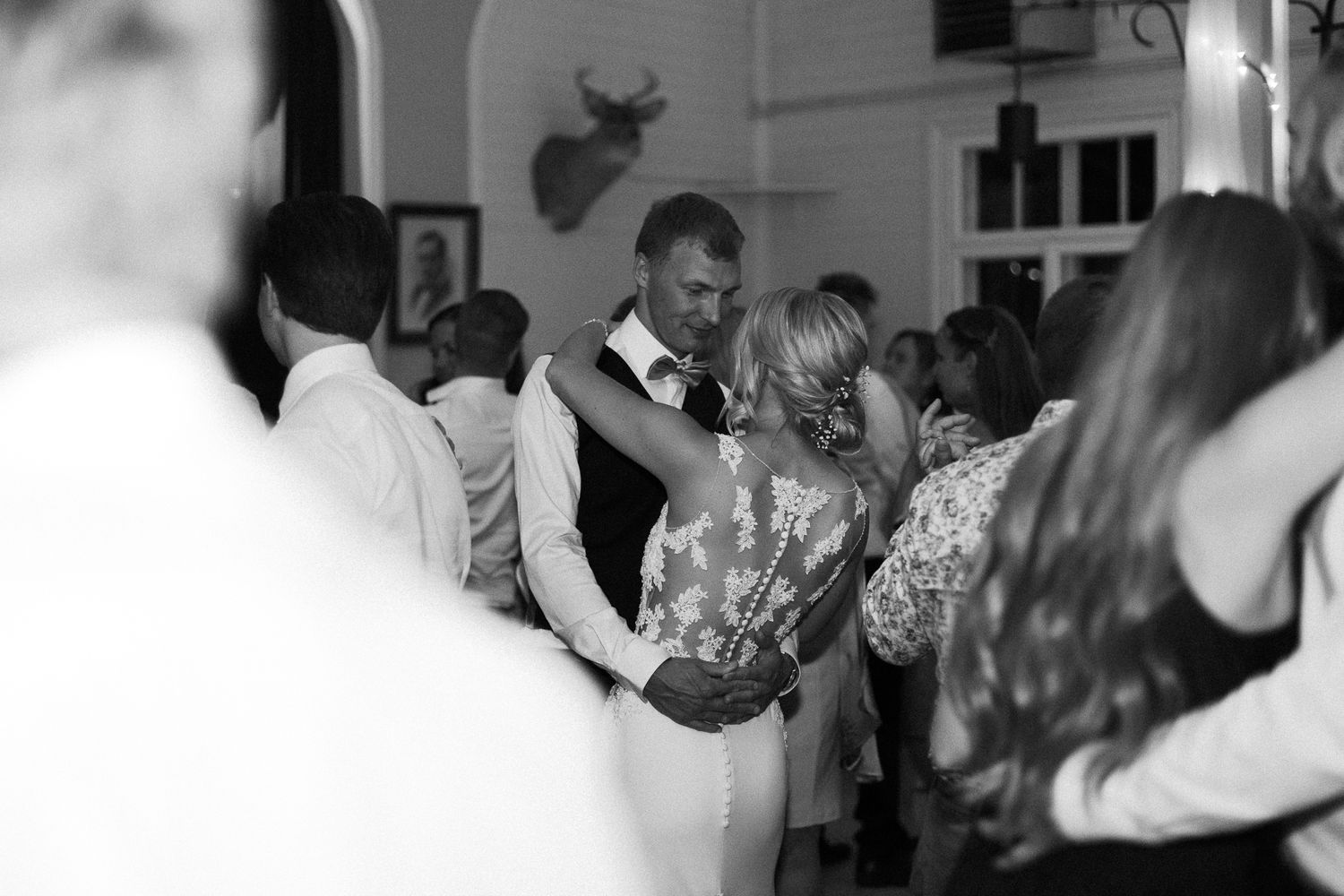 Blurred black and white image of wedding guests dancing at a reception.