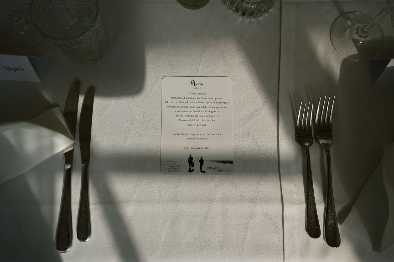 Place settings with silverware and menus arranged on crisp white tablecloths.