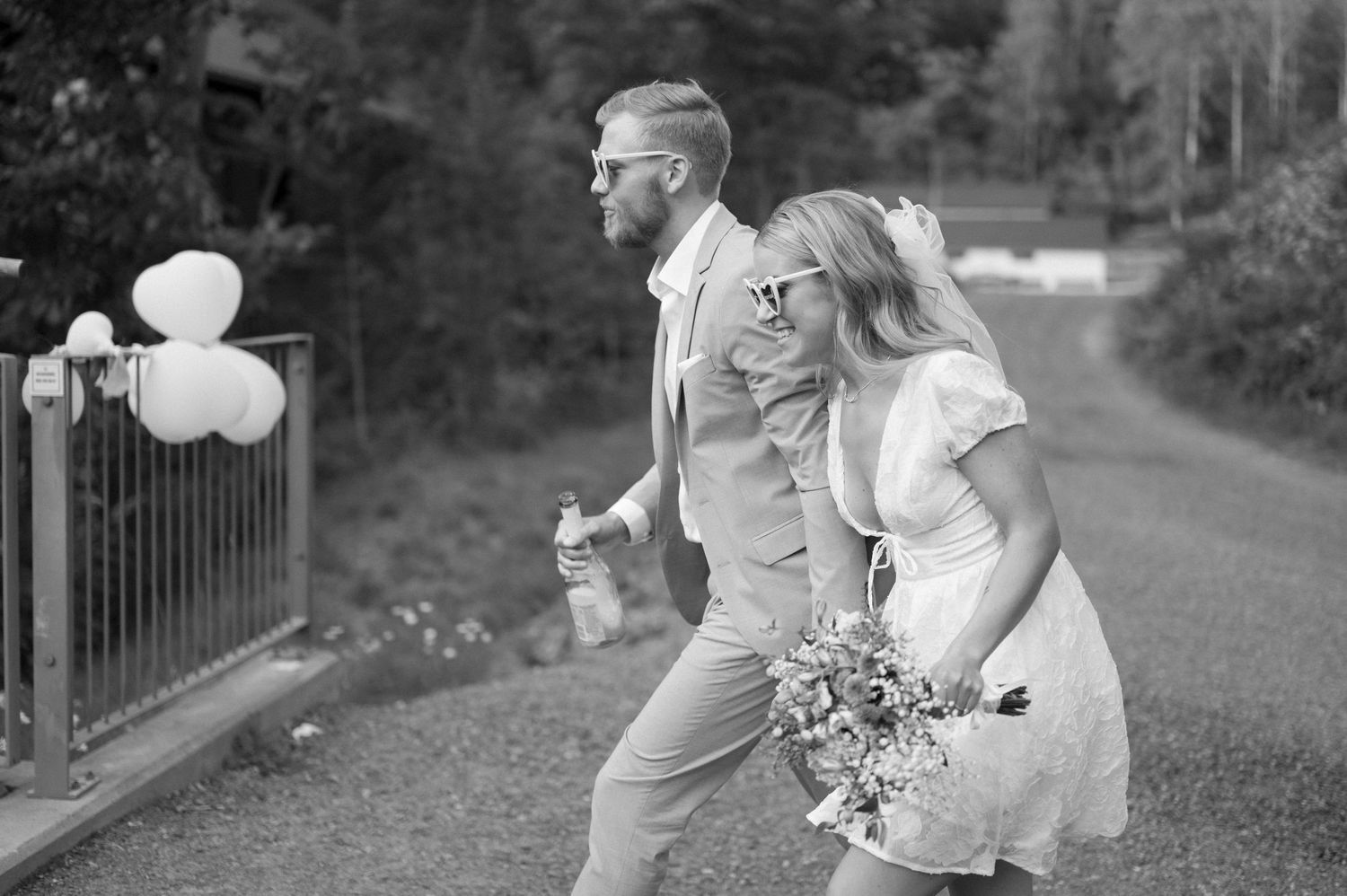 A black and white photo captures celebratory moments with balloons and flowers outdoors.