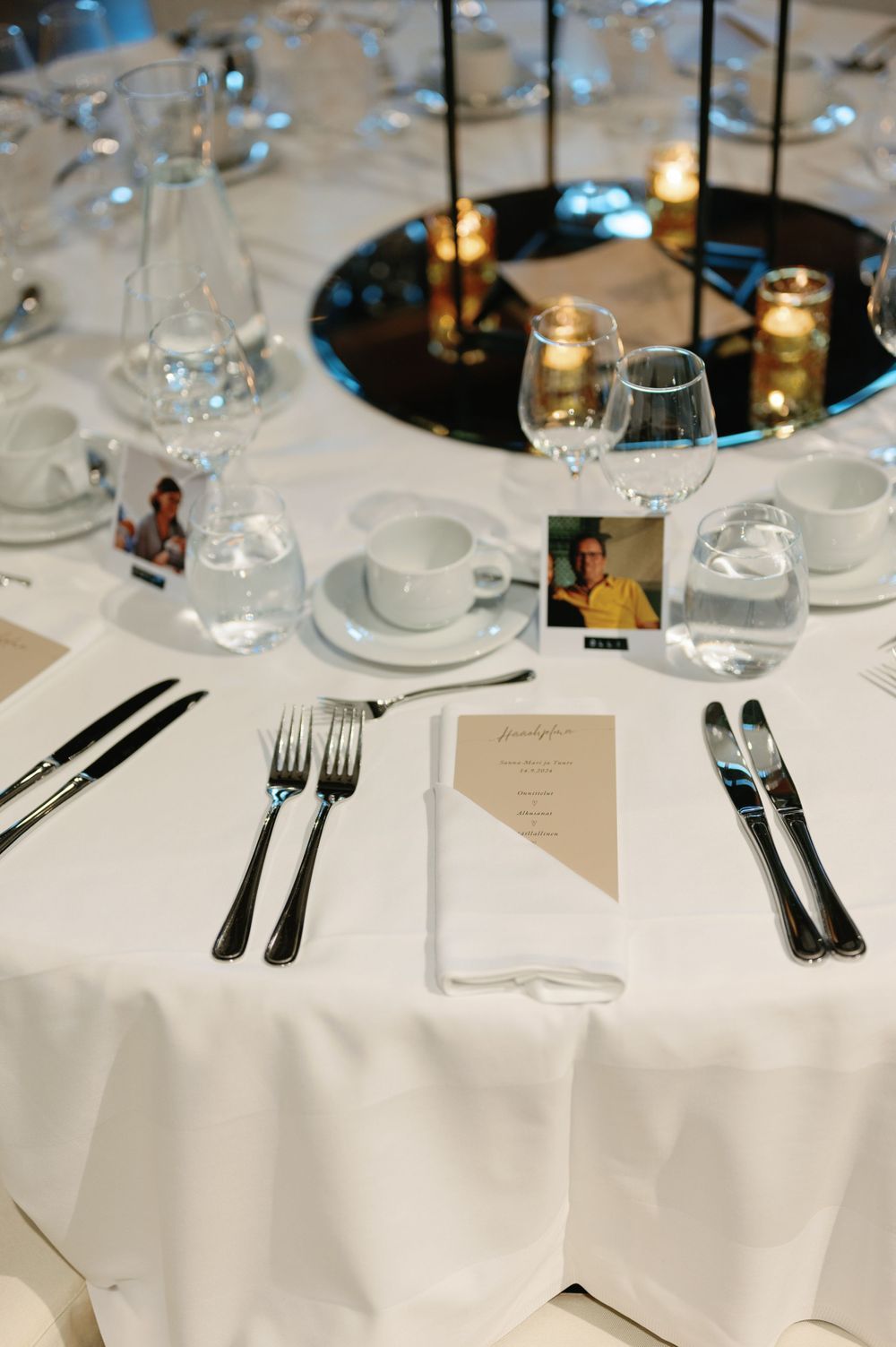 Formal table setting with white tablecloth, silverware and wine glasses.