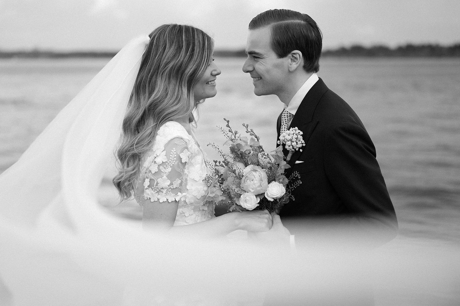 Elegant waterfront wedding photography sequence capturing tender moments between bride and groom.