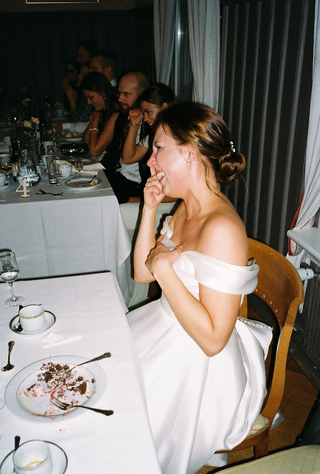 Wedding guests enjoying dinner at tables with white linens.