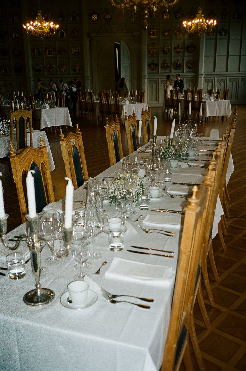 Formal table settings with white linens, glassware and taper candles in an elegant dining room.