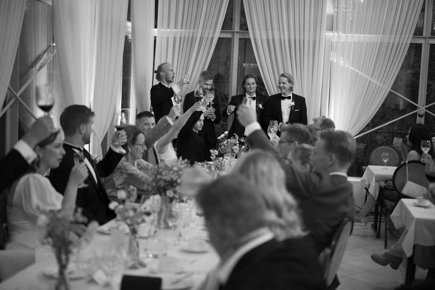 Wedding reception guests celebrating in an elegant white-draped venue.