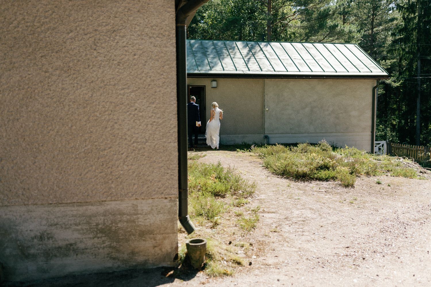 Exterior view of a small white building with a gravel path in a rural setting.