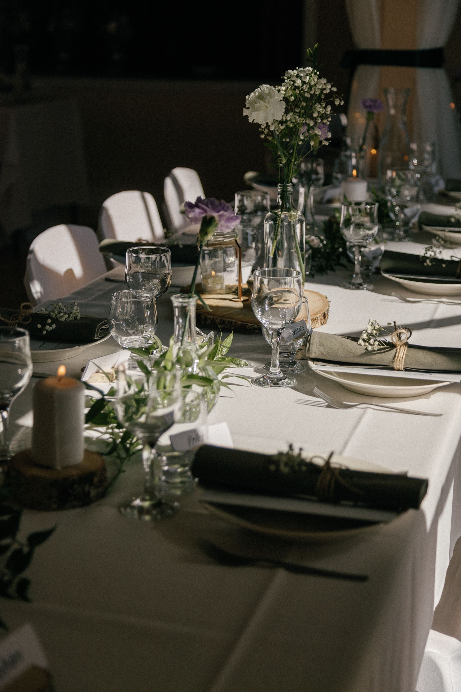 Wedding reception table with white linens, floral arrangements, and vintage glassware.