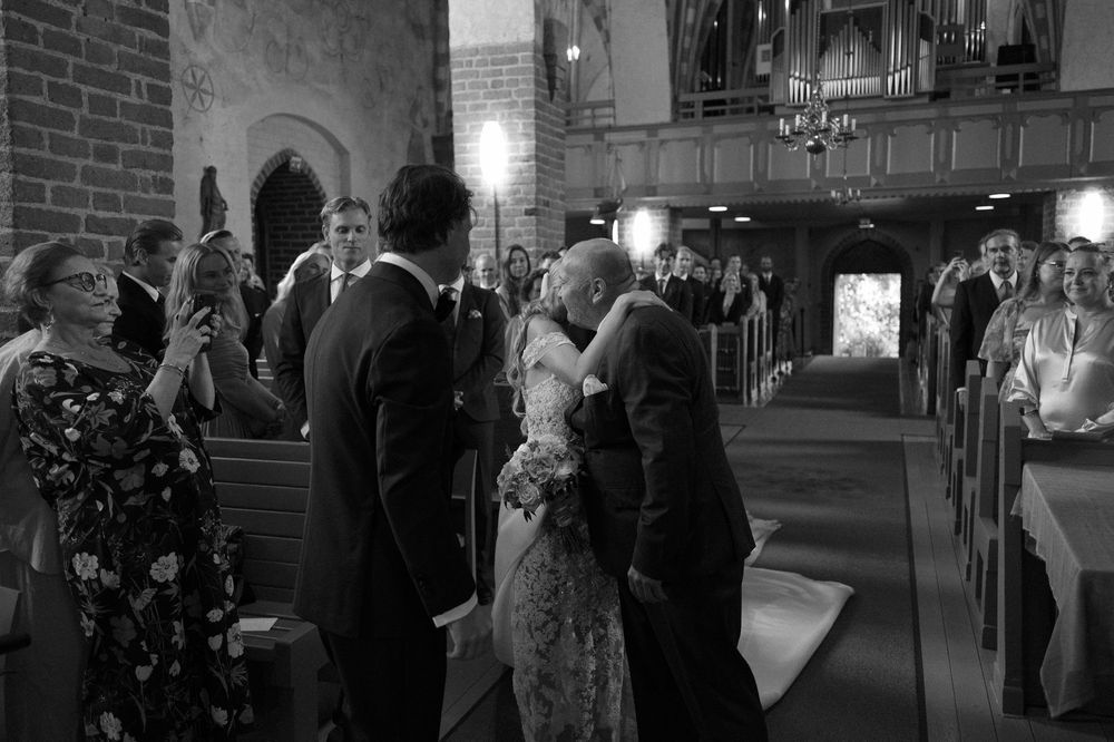 Wedding ceremony procession in a traditional church with Gothic architecture and brick walls.