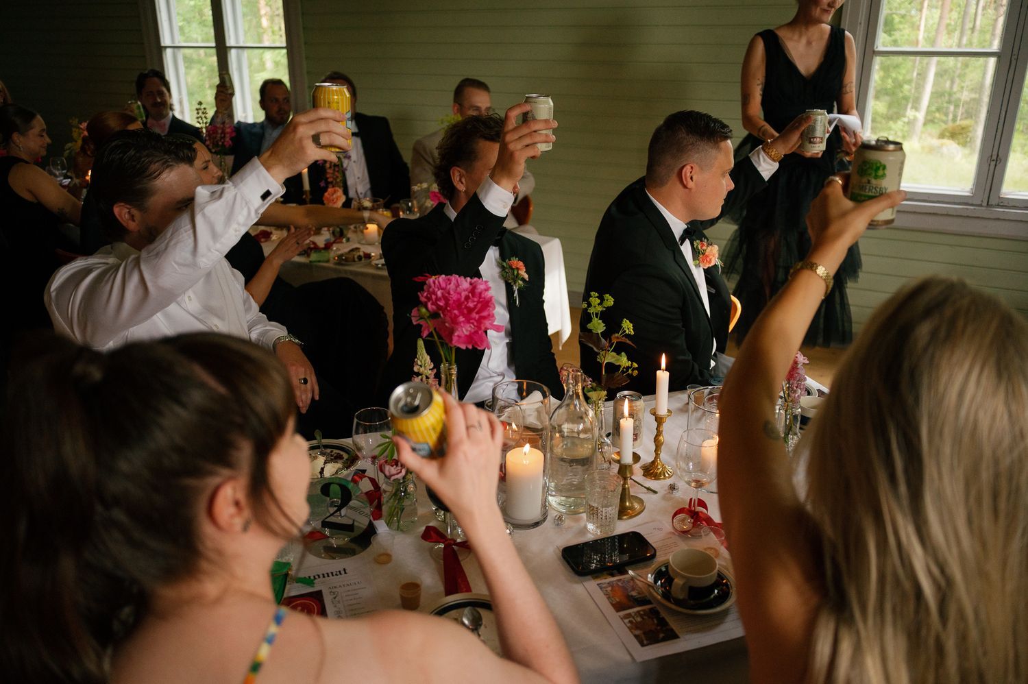 Wedding reception guests seated at tables in rustic indoor venue.